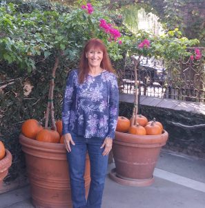 Ana Lash stands in front of plants and pumpkins