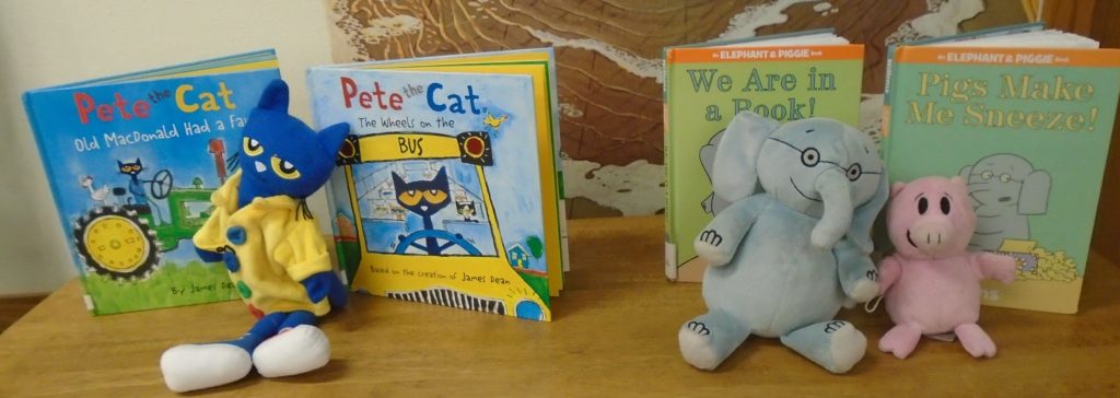 A blue stuffed animal and two books on the table.