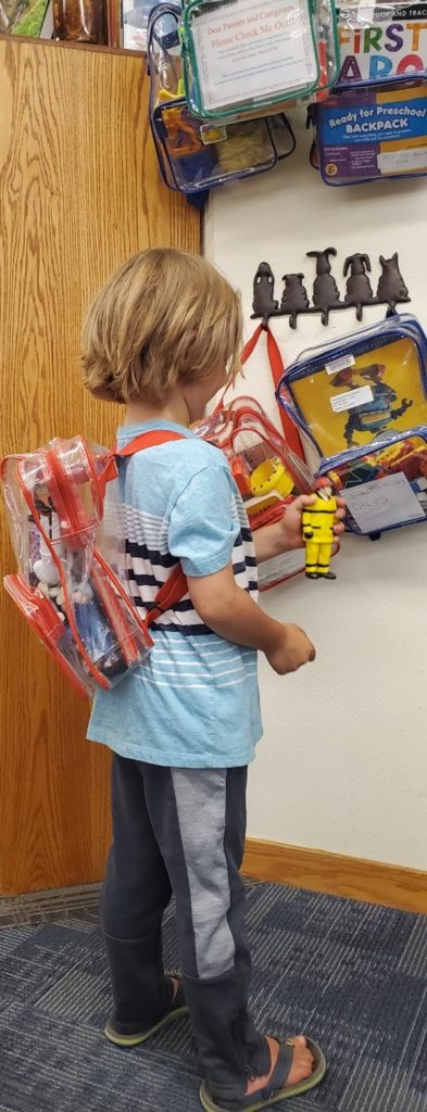 A young boy with a backpack and some toys