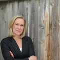 A woman standing in front of a wooden fence.